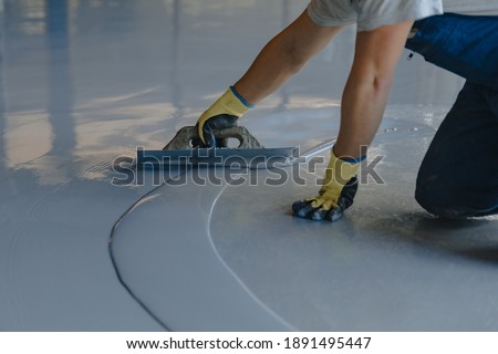 The worker applies gray epoxy resin to the new floor Royalty-Free Stock Photo #1891495447