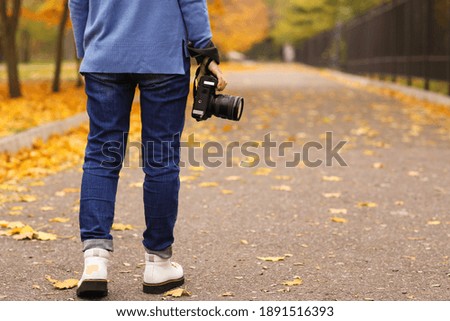 Photographer with professional camera outdoors on autumn day, closeup. Space for text