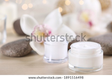 Beautiful composition with cosmetic products, spa stones and flowers on table, closeup. Space for text