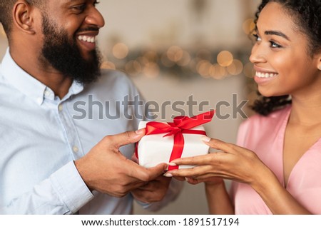 Closeup of happy lovers exchanging gifts on holiday, anniversary, St Valentine's day or birthday. Happy attractive young african american female giving or receiving present surprise from her man