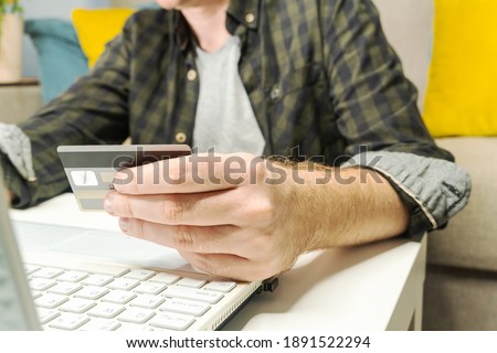 Hand holding credit card and using laptop. Online shopping or e-commerce. Man spending money from home.