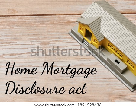 Text Home Mortgage Disclosure Act on wooden background with house miniature.Business and property concept.