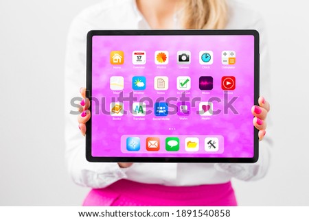 Woman holding tablet with sample home screen app icons