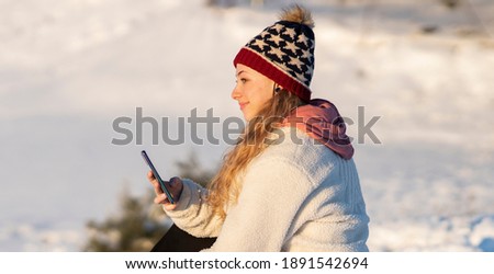 woman with mobile phone smartphone in snow