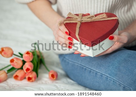 Beautiful girl open red heart gift box. Valentine's day. Happy Birthday. Girl receives a gift at home.