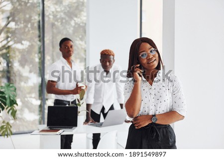 Woman talking by phone. Group of african american business people working in office together.