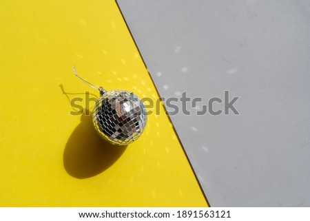 One disco balls on ulitimate gray and illuminating yellow background