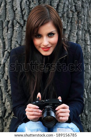 Young brunette girl using a classic camera