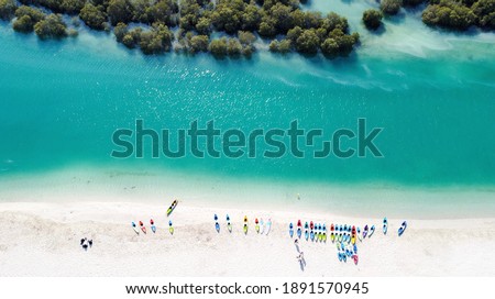 White sand beach on a sunny winter day lined with kayaks on one side and mangrove forests on another.  Royalty-Free Stock Photo #1891570945