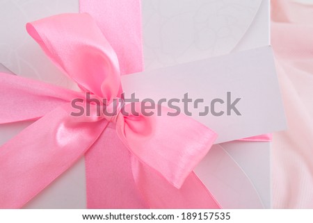 close up of gift box with pink ribbon and blank greeting card