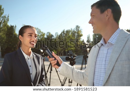 Professional journalist interviewing young woman on city street