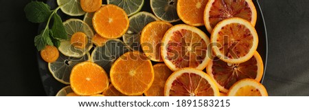 Slices of citrus fruits, top view on black background. Horizontal flat lay with different citrus, lime, orange Royalty-Free Stock Photo #1891583215