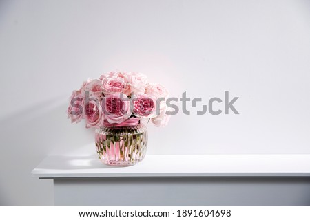 Rose White Pink O'hara in the round glass transparent vase is on the fireplace . Copy space