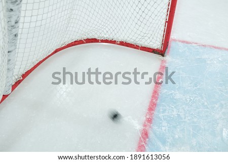 Blurred motion of puck moving over ice rink for playing hockey towards net of rival and going to make goal during play on contemporary stadium