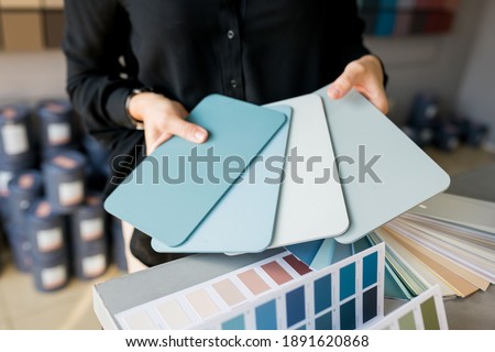 Close up of Young woman interior designer choosing color swatch for wall. House renovation concept