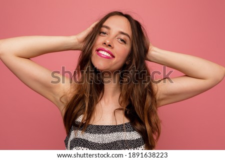 Happy incredible woman with wavy hair posing over pink background with happy smile