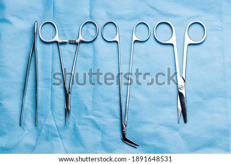 stack of surgical equipment at surgery desk. medical tools such scissors, scalpel, forceps, tweezers over blue background. surgery concept.
