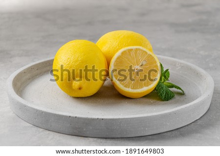 Fresh yellow lemons on a gray concrete background. The color of the year