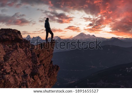 Adventurous man is standing on top of the mountain and enjoying the beautiful view. Taken on top of Cheam Peak in Chilliwack, East of Vancouver, BC, Canada. Colorful Sunset Sky Art Render Royalty-Free Stock Photo #1891655527