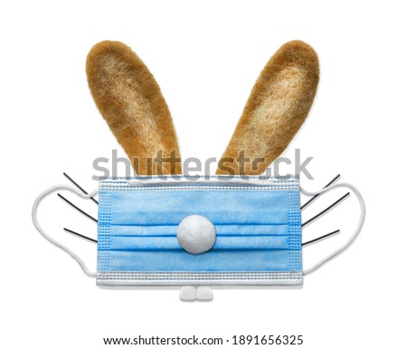 safe easter 2021 - concept - bunny with long ears is hiding behind a medical mask