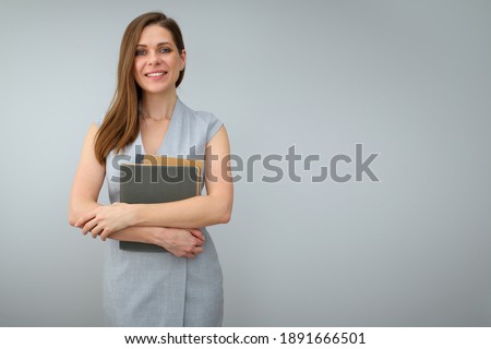 Business woman wearing grey dress and holding books standing next to the copy space. Isolated female portrait.