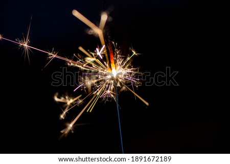 Golden colored  sparkler in front of a black background, close up, isolated
