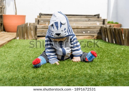 Young children playing in the garden sitting on the grass