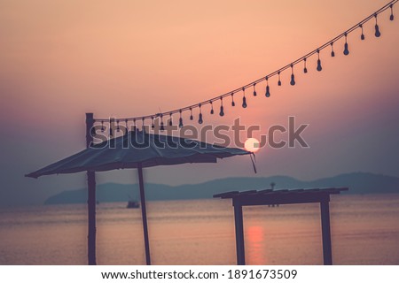 Silhouette beach umbrella on sunrise over tropical sea in Thailand background