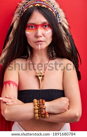 young ethnic lady with roach on her head isolated over red background, female in top posing at camera, shaman