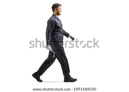 Full length profile shot of a mechanic in a uniform walking isolated on white background