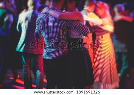 Couples dancing traditional latin argentinian dance milonga in the ballroom, tango salsa bachata kizomba lesson in the red lights, dance festival  Royalty-Free Stock Photo #1891691326