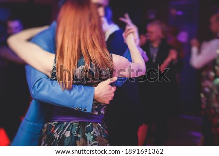 Couples dancing traditional latin argentinian dance milonga in the ballroom, tango salsa bachata kizomba lesson in the red lights, dance festival  Royalty-Free Stock Photo #1891691362