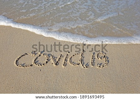Beach sand messages : Covid-19 written in the sand on beach with wave. Concepts photography. Selective focus 