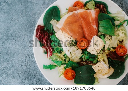Salad with herbs, cherry tomatoes, camembert and prosciutto, spinach and lettuce. Healthy food, breakfast or lunch, dietary dinner and balanced meals.