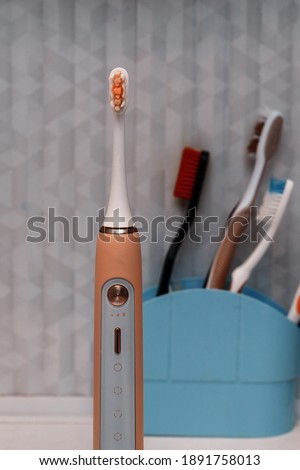 modern sonic electric toothbrush on the background of ordinary toothbrushes