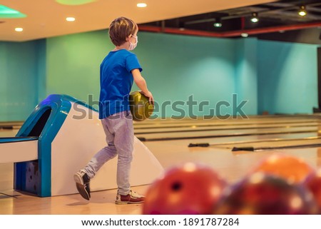 Boy playing bowling with medical masks during COVID-19 coronavirus in bowling club