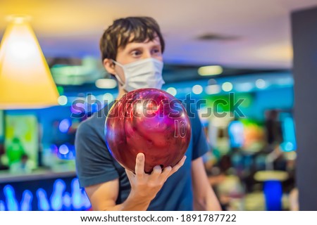 Man playing bowling with medical masks during COVID-19 coronavirus in bowling club