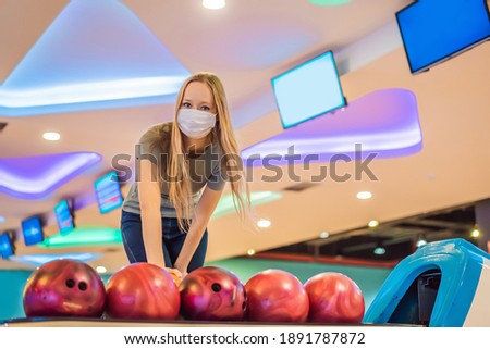 Woman playing bowling with medical masks during COVID-19 coronavirus in bowling club