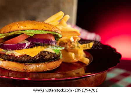 guacamole spread on cheese hamburger with fries with red background
