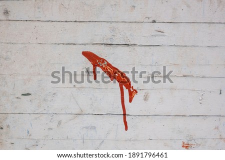 Weathered white wooden fence with one red painted brush stroke. Stock Photo.