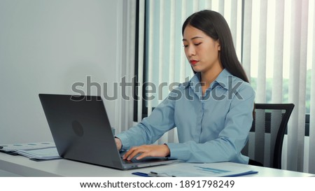 Asian women are working on laptop with seriously and have a serious demeanor in office.