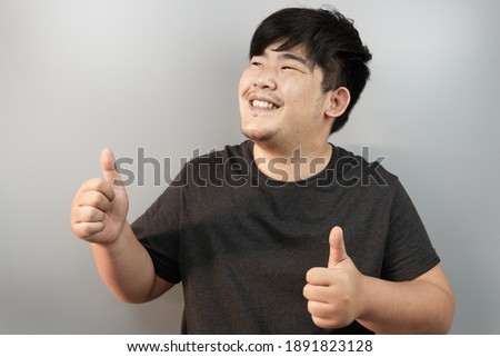 portrait asian man look up and thumb up to agree on isolated background in studio