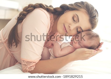 Portrait of a beautiful mother, with her nursing baby. High quality photo. Royalty-Free Stock Photo #1891829215
