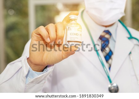 Doctor shows the antiviral drug : Male doctor wearing a mask holds a dose of COVID-19 influenza vaccine for hospitalized patients