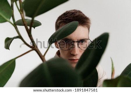 the guy looks with an angry look in round glasses through the flower