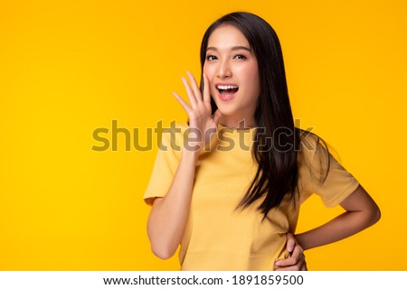 Surprised happy beauty asian woman look at camera in excitement Expressive facial expressions Presenting some product Beautiful girl act like a telling something Isolated on yellow background 