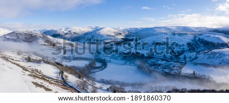 Ystwyth valley in Ceredigion, Wales, with mist in the valley bottom and snow on the surrounding woodland and hills Royalty-Free Stock Photo #1891860370