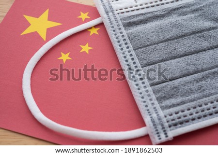 Close up face mask on China national flag background. Global novel coronavirus (Covid-19) outbreak pandemic effect to world economy and financial crisis, investment, travel hotel business.