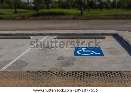 Disable person parking sign or wheelchair symbol with blurred outdoors background. 
