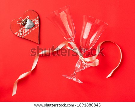 Wine glasses and a heart on a red background. The concept of a romantic dinner.